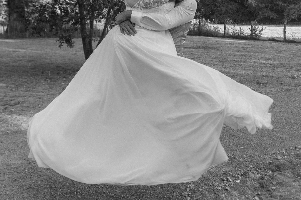 Le marié porte la mariée et fait tourner sa robe