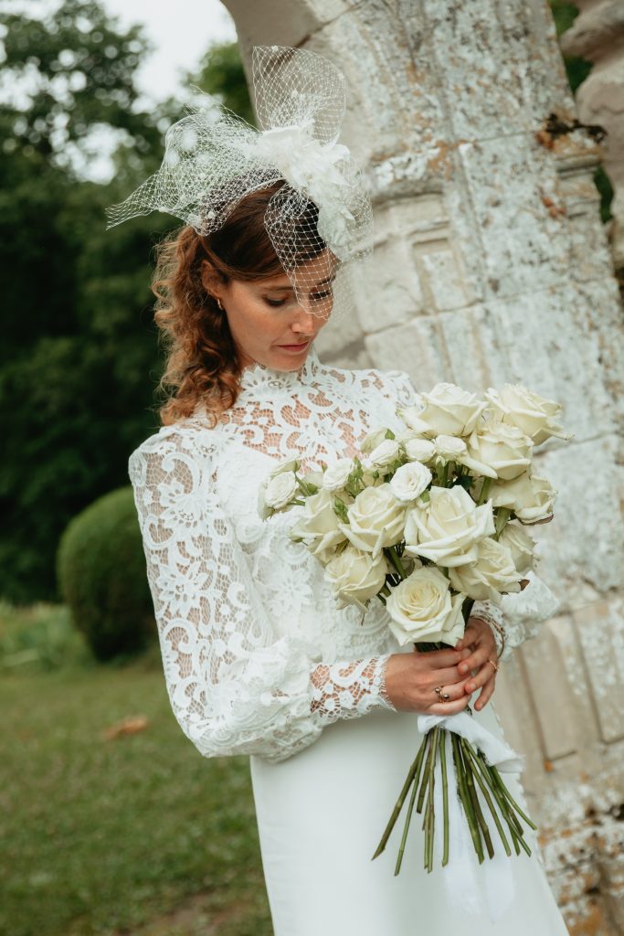 La mariée tient son bouquet de roses blanches dans les mains