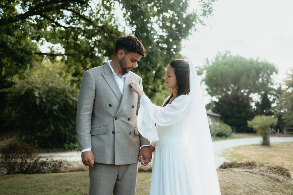 La mariée ajuste le costume de son mari pendant la séance couple