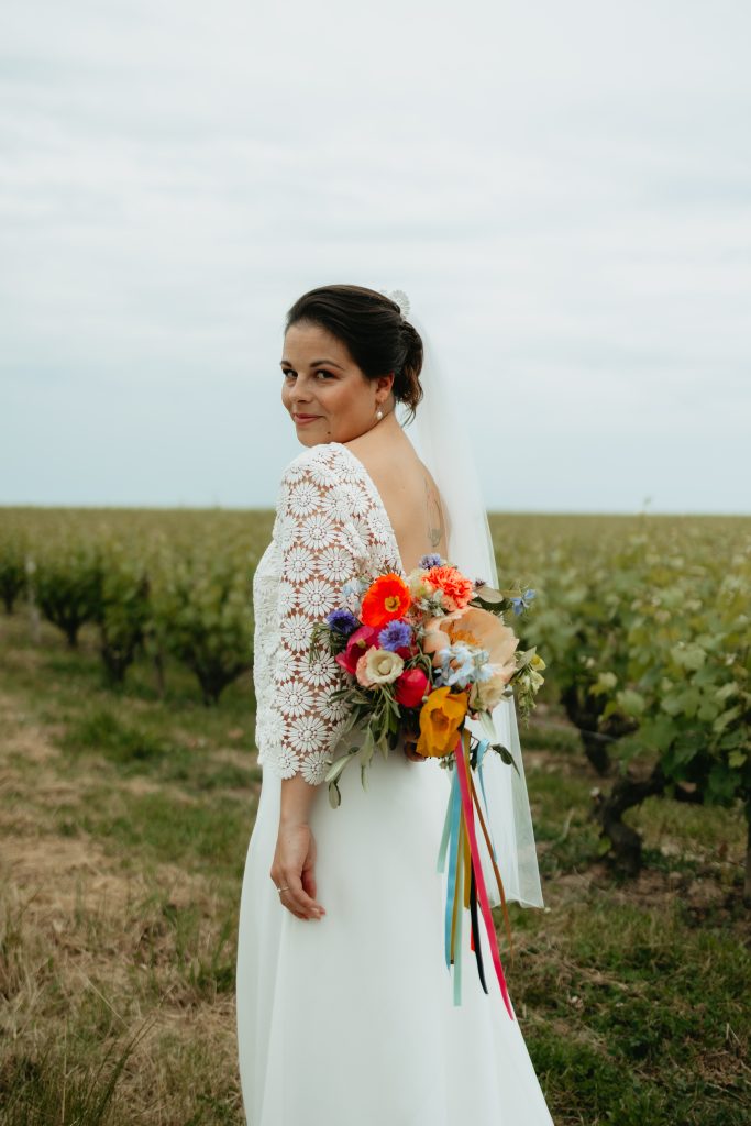 Portrait de la mariée qui mets son bouquet de fleur dans son dos