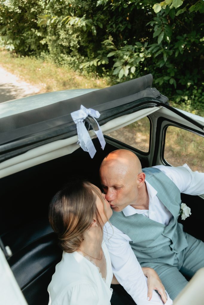 Les mariés s’embrassent dans la voiture pendant la séance couple